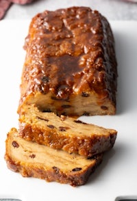 a slice of raisin cake on a white plate