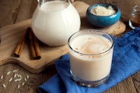 a glass of milk with cinnamon and cinnamon sticks on a wooden table