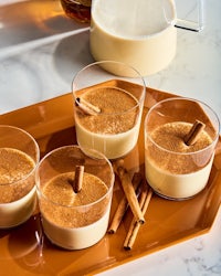 a tray with several glasses and cinnamon sticks