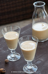 two glasses of milk on a table next to a jug